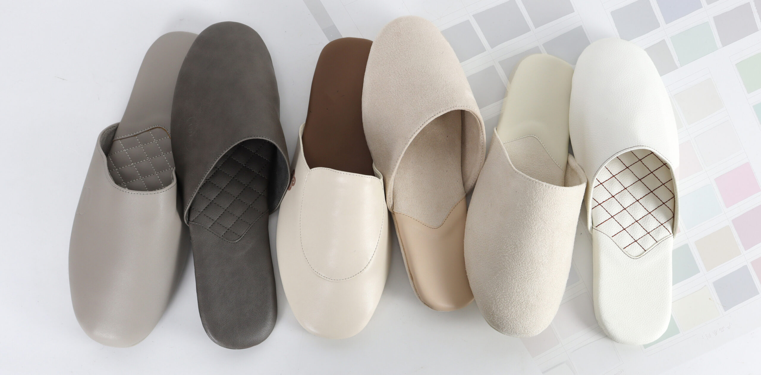 Pairs of grey and white custom mule slippers by JNP Footwear, showcasing neutral B2B options