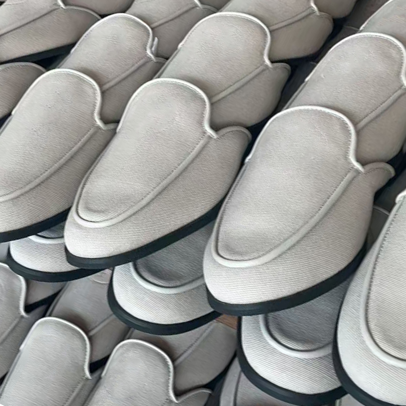 Batch of white custom loafer-style slippers with black piping in production at JNP Footwear