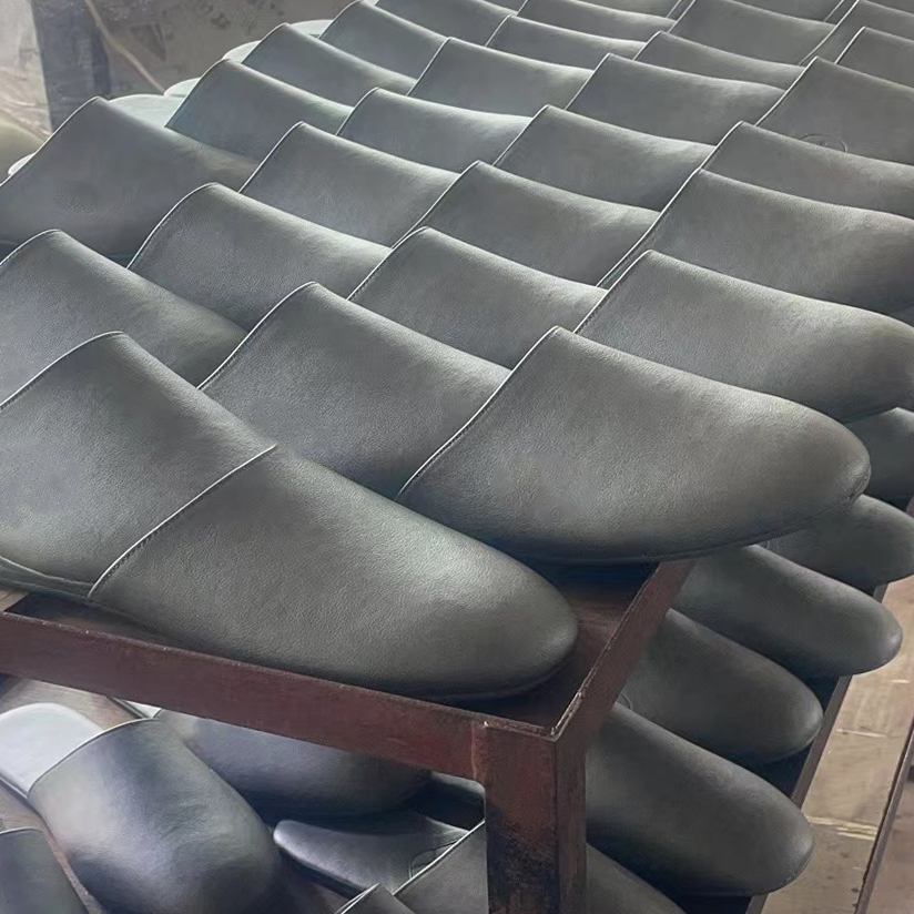 Batch of grey custom leather-like slippers on shelves, ready for B2B wholesale by JNP Footwear